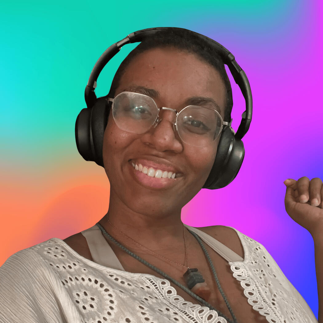 Photo of TylerVoiceActs, Medium Dark Skinned Femme with short shaved black hair and thin metal octagonal glasses smiling with black over the ear headphones on a multicolored teal, orange, and magenta background.